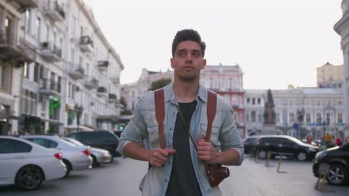 Attractive Young Handsome Man Tourist with Backpack Walking in City Center and Looking Around