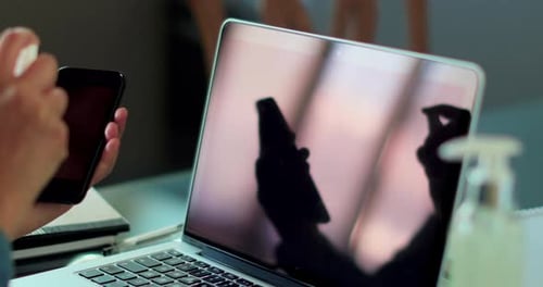 Person Cleaning Smartphone Screen in Office Setting