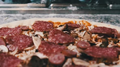 Appetitlicher roher Pizzateig mit gehackten Zutaten liegt auf der Küchenoberfläche.