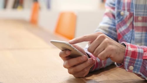 Man's Hands Using Smartphone on Table Indoors