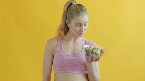 Woman in Workout Clothes Holds Bowl of Salad