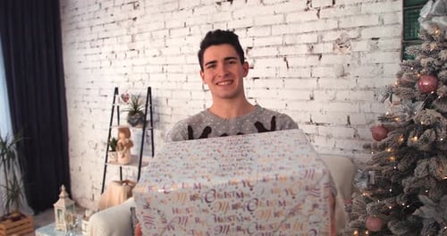 Man Smiles Holding Wrapped Christmas Gift