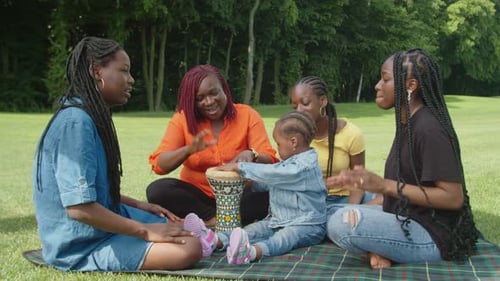 Family Fun: Women and Toddler Drumming in Park