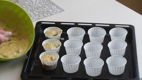 A Woman Puts The Dough Into Muffin Tins On A Baking Sheet.