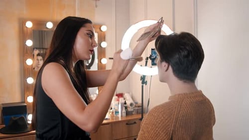 Woman Make Up Artist Applying Contour Shades on a Cheekbones of Male Model Using a Brush