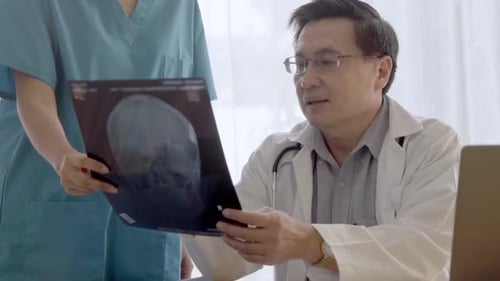Doctor Reviews X-Ray with Assistant in Modern Office