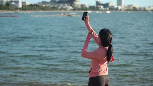 Young Woman Takes Selfie at Beach Near City