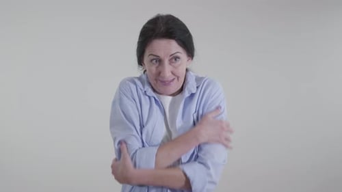 Femme caucasienne gelée se frottant les épaules sur fond blanc. Jeune femme adulte montrant un temps froid