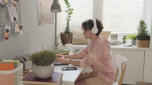 Young Adult Typing on Laptop at Home Desk