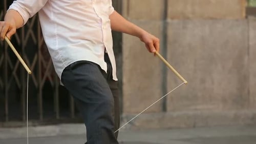 Guy doing street show with hourglass cylinder throwing and catching with thread