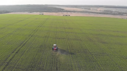 Luftaufnahme des Traktors, der die Chemikalien auf der großen grünen Wiese düngt.