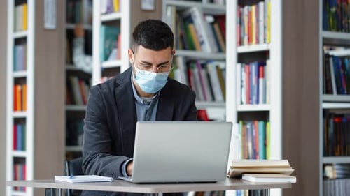 Student Studying in Library Using Laptop During Pandemic
