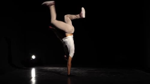 Junger Mann tanzt Breakdance im schwarzen Studio