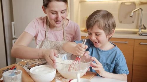 Smiling Child and Adult Whisking Batter in Kitchen