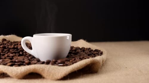 Steaming Coffee Cup on Burlap with Roasted Beans