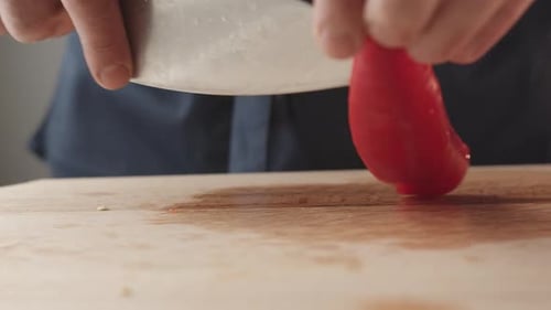 View of the Young Chef Cut Thin Slices of a Piece of Red Pepper with a Knife