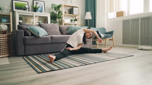 Woman Stretching on Yoga Mat in Bright Living Room
