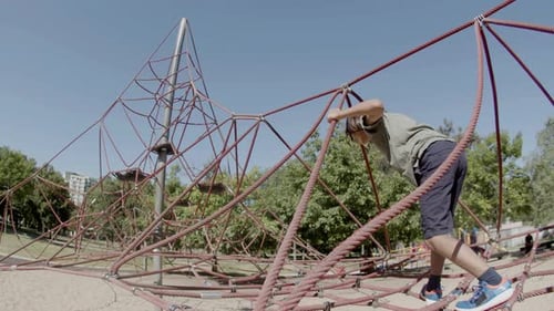 Tracking Shot of Boy Climbing Rope Attraction on Playground