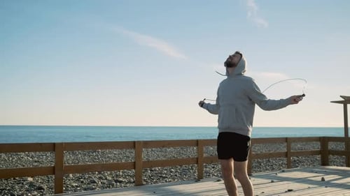 Enduring Man Is Leaping Near Sea Spinning Rope Around Himself