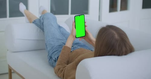 Close-up Shot of Green Screen Template Smartphone in Female Hands at Home, Girl Is Watching Content