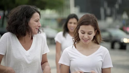 Cheerful Friends Walking on Street with Phones and Talking