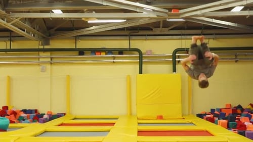 Man Performing Gymnastic Flips on Trampoline Indoors