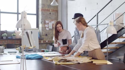 Team of Dressmakers Discussing Fabric in Sewing Studio