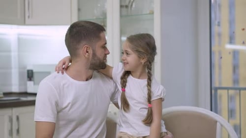 Loving Daughter Kisses Father on Cheek in Kitchen