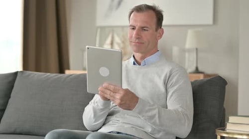 Mature Adult Using Tablet at Home on Couch
