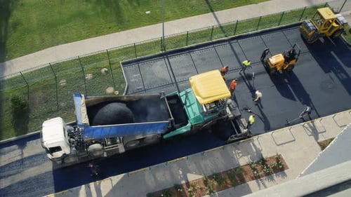 Zeitraffer. Bauarbeiter bei der Arbeit auf der Straße. Asphaltfertiger Aufbringen von heißem Asphalt auf der Autobahn