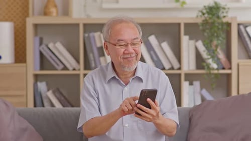 Senior Man Using Smartphone on Couch Indoors