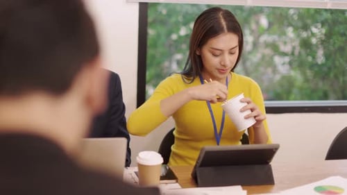 Young Woman Eating Noodles at Office Meeting