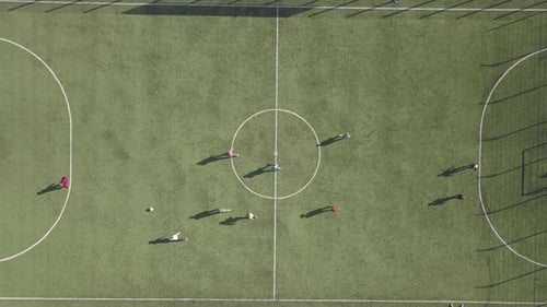 Top down aerial view of green football sports field and players playing football. Small