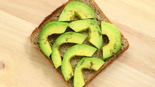 Sandwich with slices of avocado with pepper and salt top view