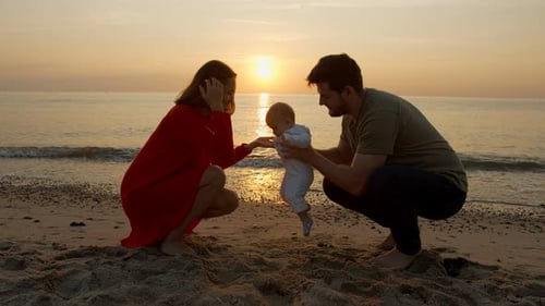 Young Family on the Background of Sunset By the Sea