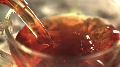 Pouring Amber Liquid into a Glass Teacup