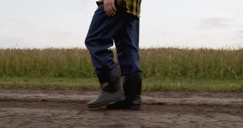 Farmer Walking on Dirt Path Through Country Field