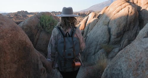 Junge lächelnde Frau mit Rucksack wandert bei Sonnenaufgang im malerischen Rocky Canyon