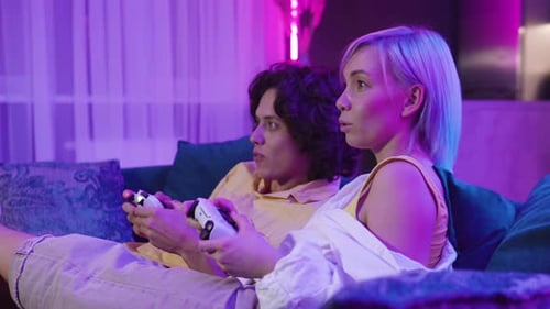 Young Couple Woman and Man Inside of Room Exited Look on a Tv Screen Playing Video Games at Home