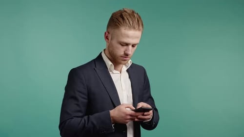 Handsome Business Man Using Smartphone on Blue Studio Wall