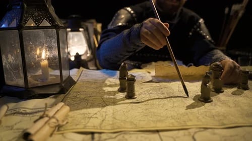 Man Plans Strategy by Candlelight with Map and Figures