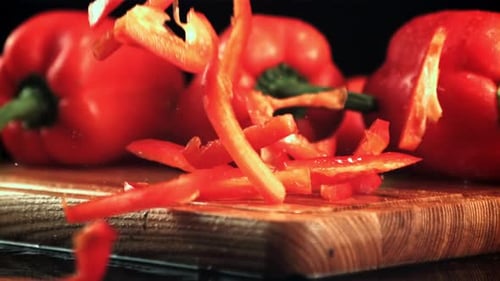 Falling Slices of Red Bell Peppers on Wood