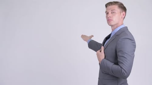 Profile View of Young Handsome Businessman in Suit Showing Something