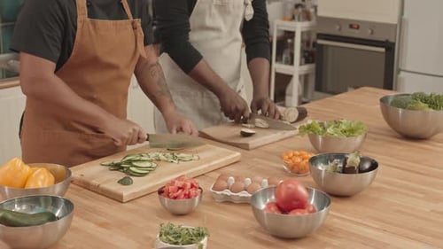 Adults in Kitchen Slicing Fresh Vegetables for Meal