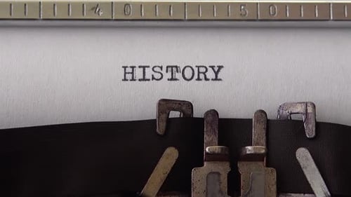 Typing word HISTORY on retro typewriter. Close up.