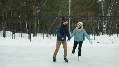 Slow Motion of Happy Man and Woman Having Fun with Ice-skating in Winter Park