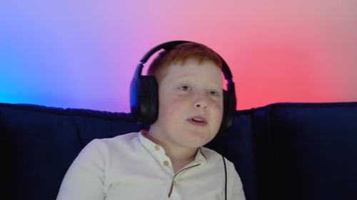 Close Up Portrait of a Little Boy Playing Online Computer Video Game in the Evening at Home