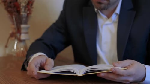 Man in Suit Reading a Book Indoors