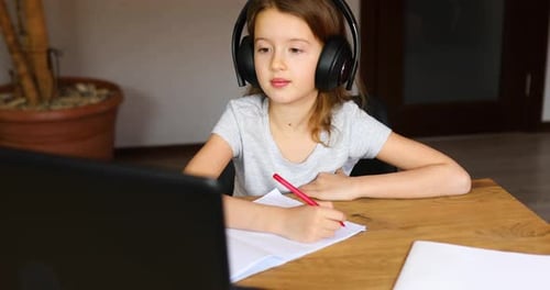 Girl Doing Homework at Desk with Headphones