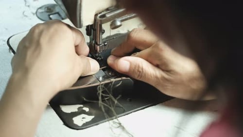Close-Up Of Tailor Working On Sewing Machine in leather factory background